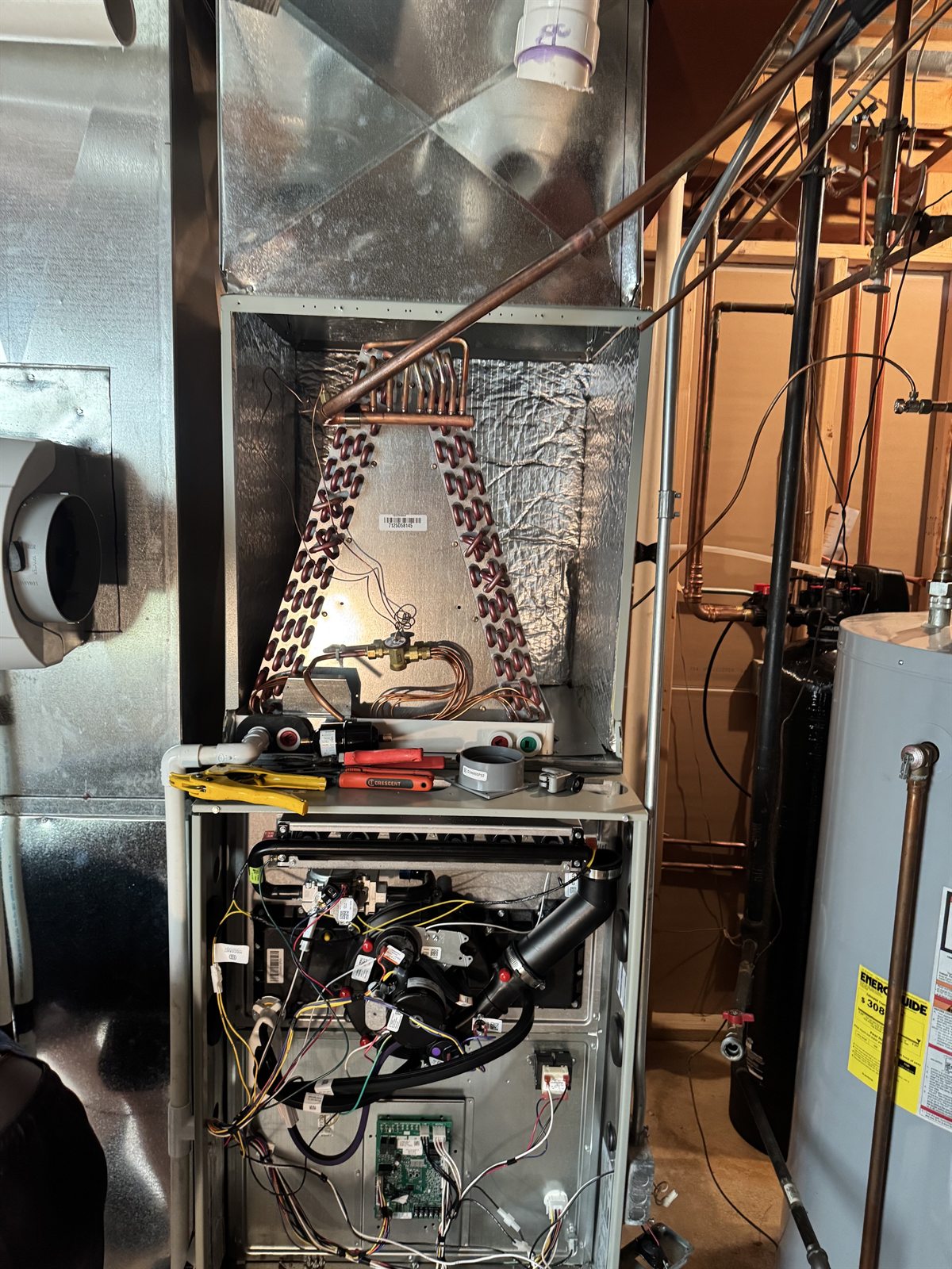 Open furnace cabinet showing the evaporator coil, controls, and service tools