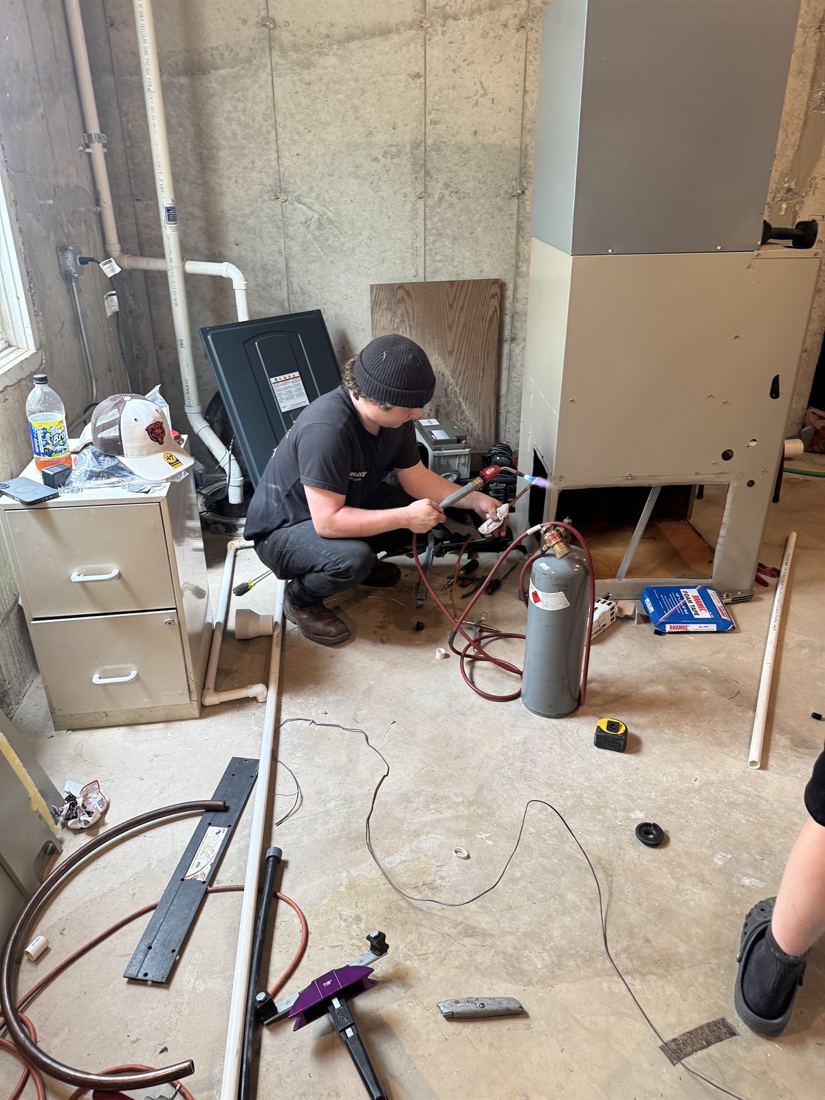 Shadow technician brazing copper refrigerant lines during a residential HVAC installation